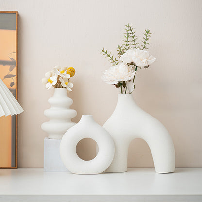 Tre vita keramikvaser med blommor på en hylla