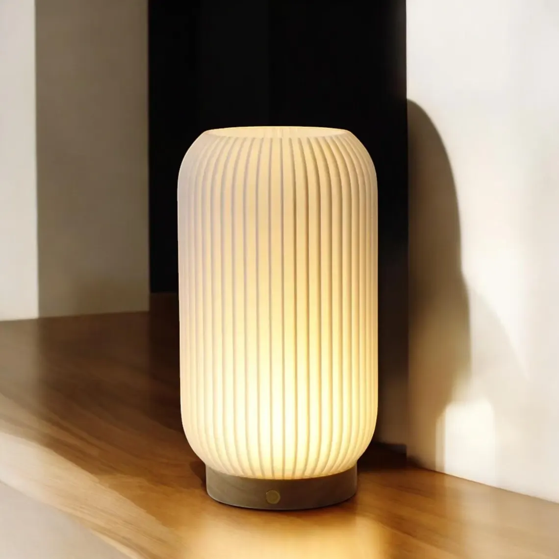 Ribbad bordslampa i opalvitt med träbas, tänd på trähylla