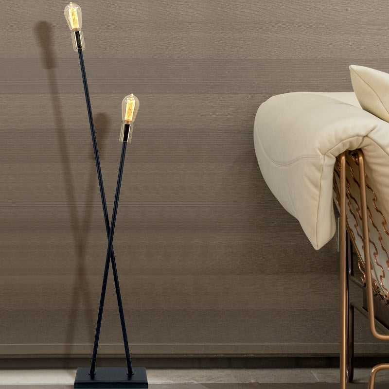Korsad stavgolvlampa i svart metall i vardagsrum